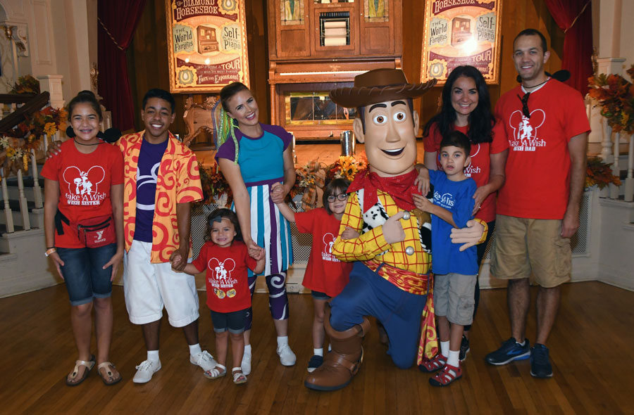 Nine-year-old Grant and his family pose with Woody and one of the Move it! Shake it! MousekeDance it! Street Party team during Grant's Make-A-Wish trip 