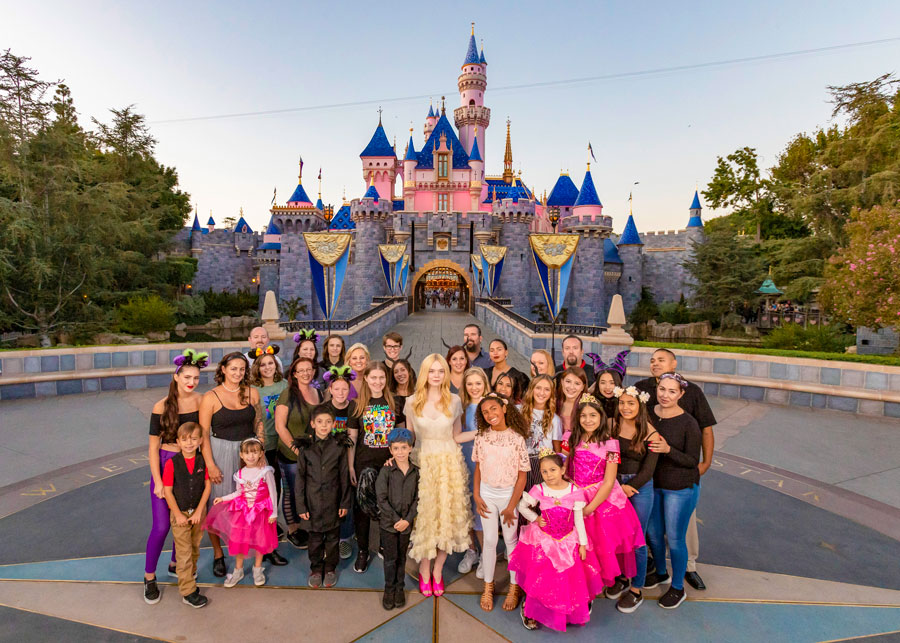 Actress Elle Fanning poses with fans in front of Sleeping Beauty Castle at Disneyland park