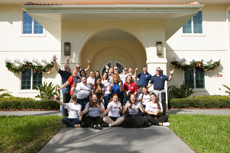 Group of Walt Disney World cast members pose in front of Orlando Fisher House after decorating for the holiday season