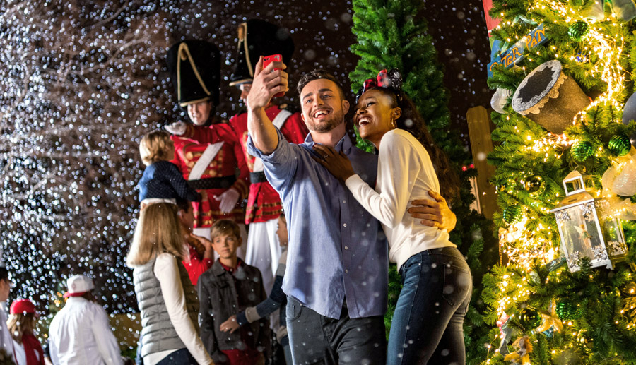 Guests take a photo and explore the Disney Springs Christmas Tree Trail