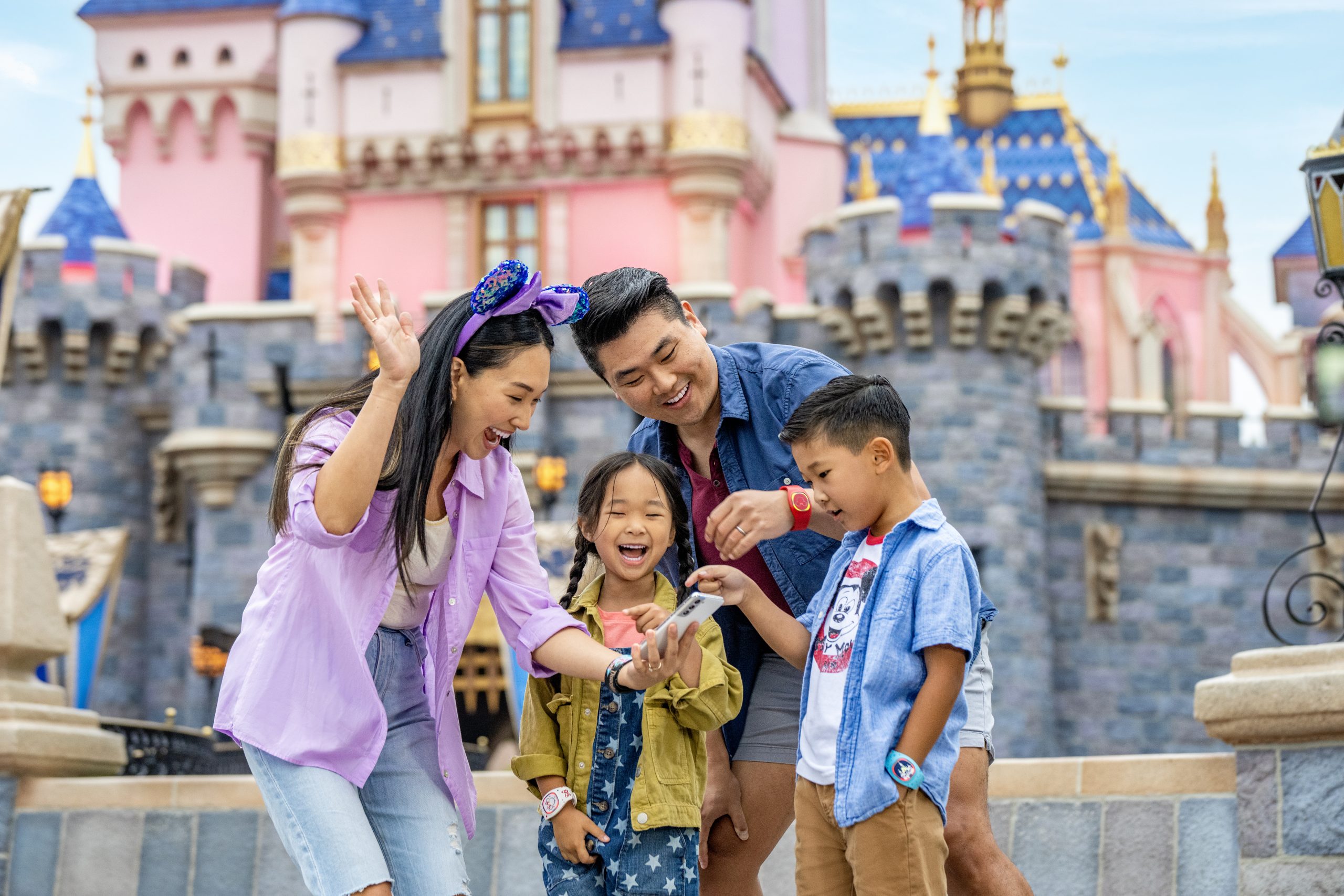 A family excitedly gathers in front of Sleeping Beauty Castle. 