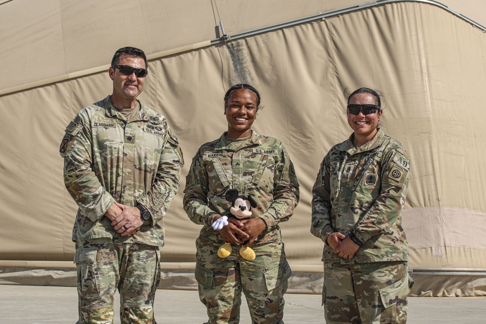 Sgt. Lamari Harris, with members of her unit, posing with the Mickey Mouse plush that came in the care package. (Photo Credit: SSG Catessa Palone & SGT Vincent Levelev – 82nd CAB Public Affairs)